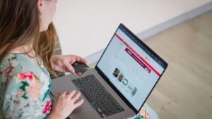 Woman in floral dress shopping online with a laptop and credit card indoors.