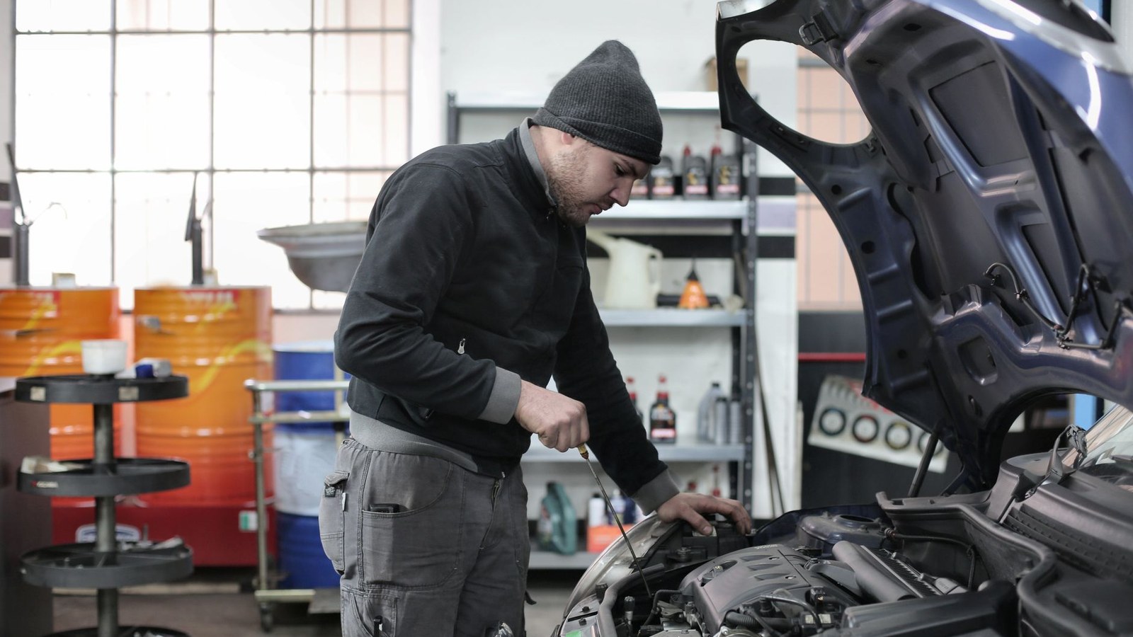 Mechanic working under the open bonnet of a car in an independent repair workshop
