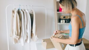 A retail worker packing clothing into boxes inside a nearly empty fashion store with bare racks in the background