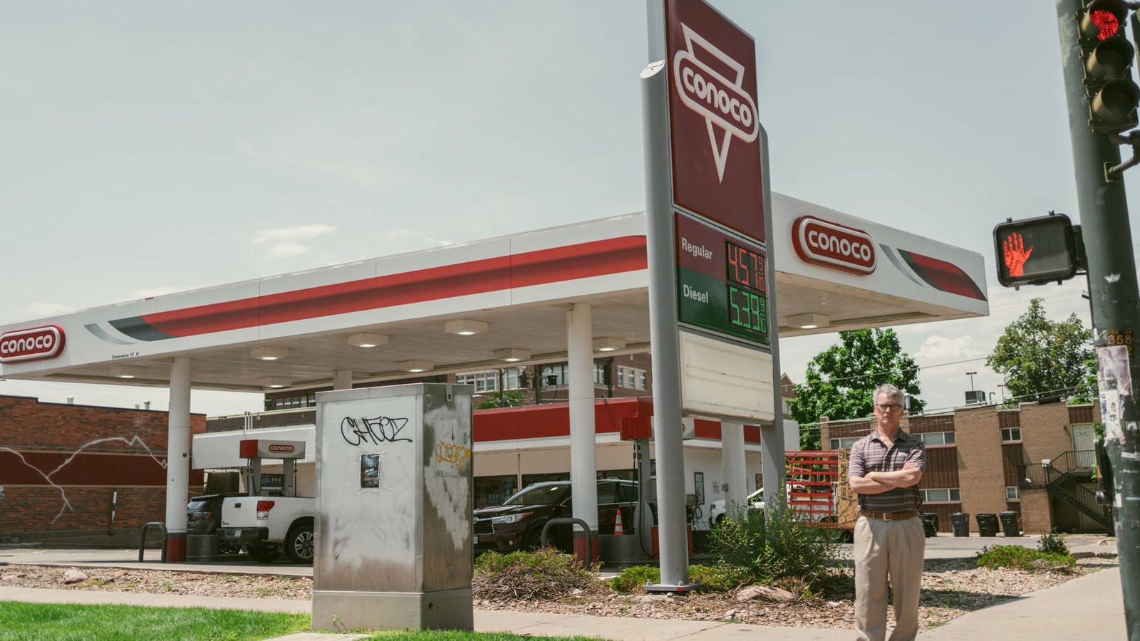 A woman holding fuel receipts stands next to a van at an Australian petrol station, looking concerned as she reviews the costs